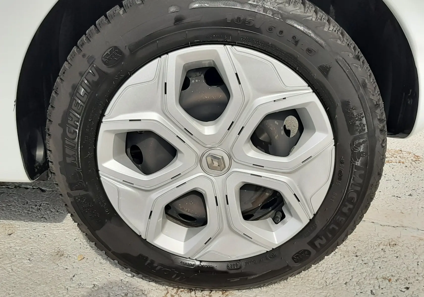 Gros plan sur le phare avant gauche allumé de la Renault Twingo III blanc cristal, avec calandre noire et carrosserie lisse.