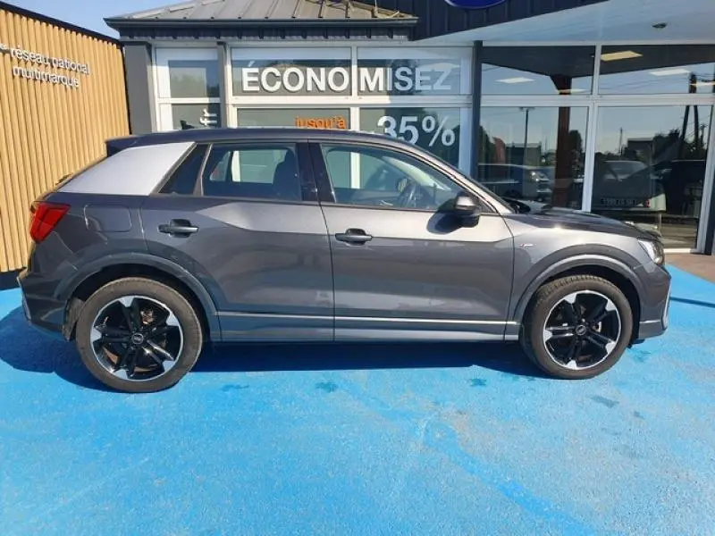 Audi Q2 30 TDI gris Manhattan métallisé vue de profil côté gauche, avec jantes noires et toit contrasté gris clair.