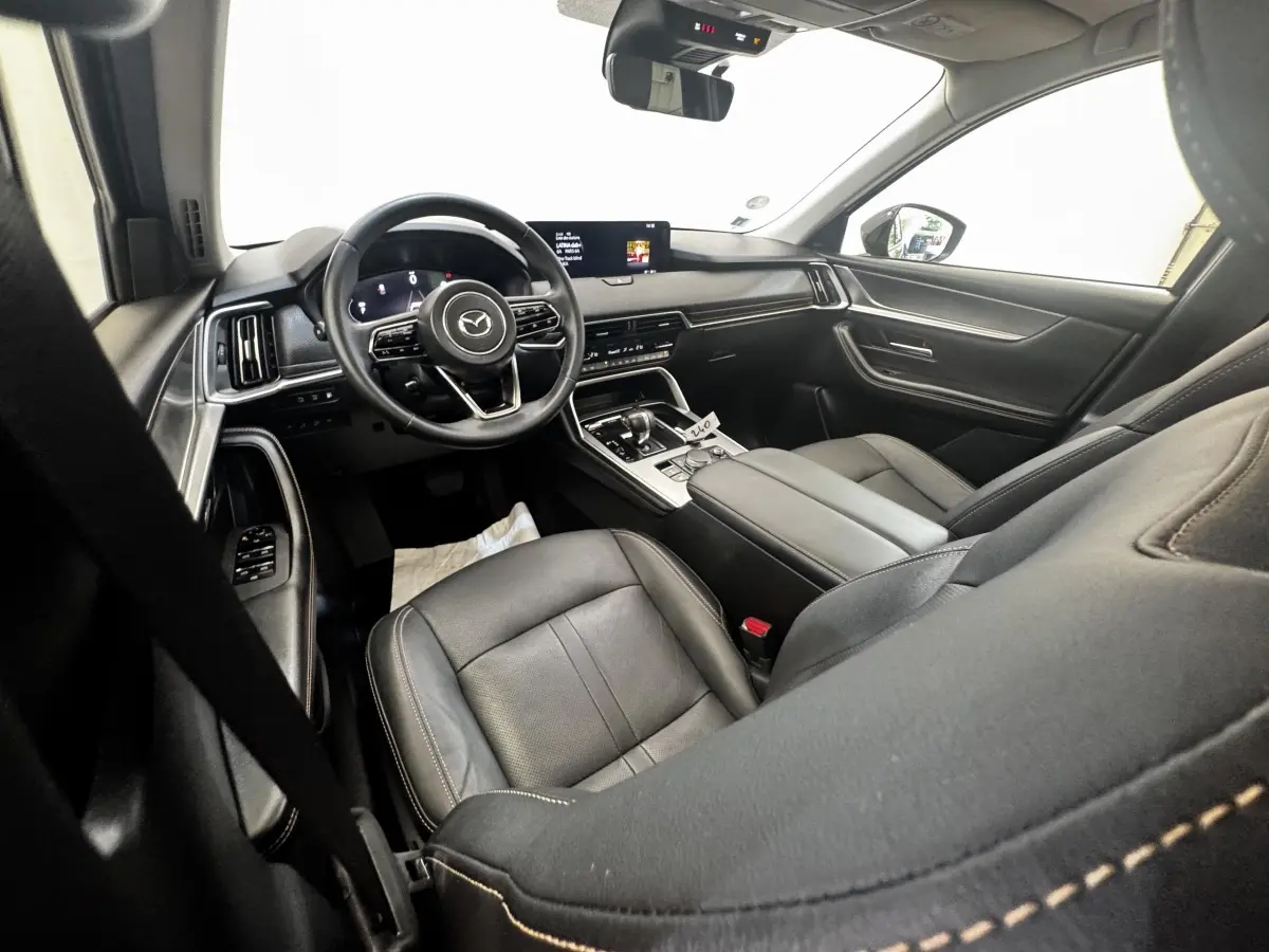 Intérieur noir du Mazda CX-60 2024, vue côté conducteur, tableau de bord moderne avec écran tactile central.
