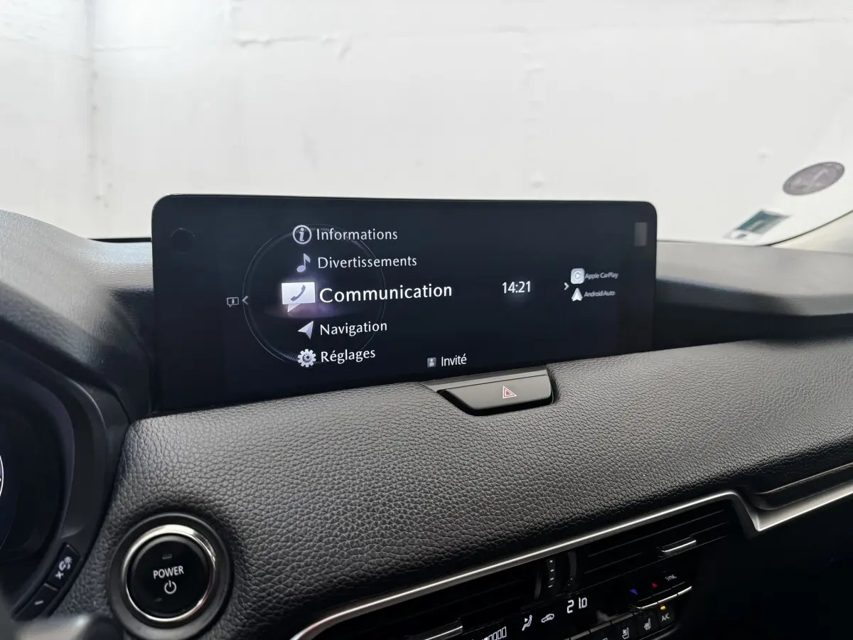 Vue rapprochée de l’écran tactile central du tableau de bord noir du Mazda CX-60 2024 affichant le menu Communication.