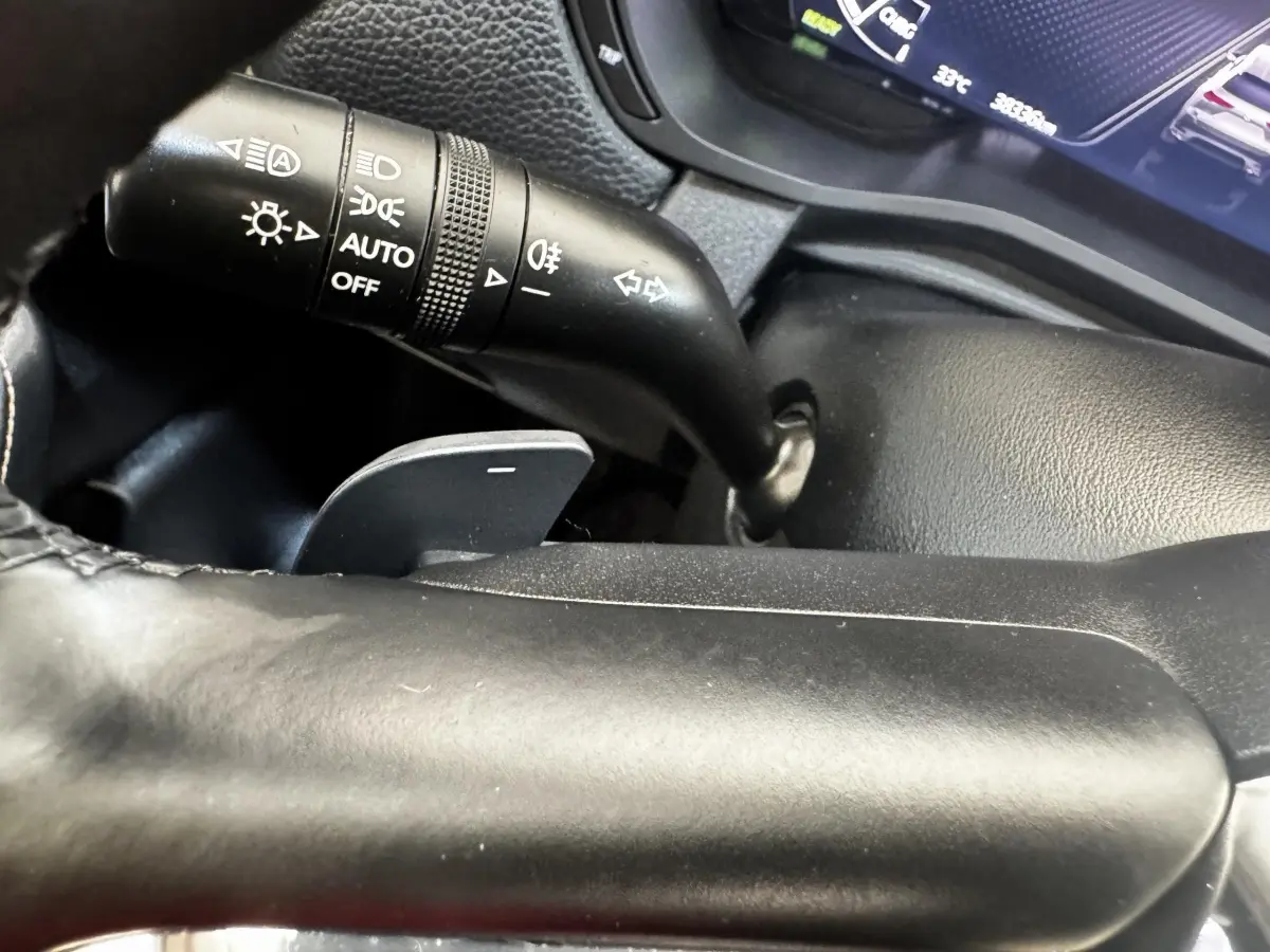 Gros plan sur la manette de commande des phares et clignotants du tableau de bord noir du Mazda CX-60 2024.