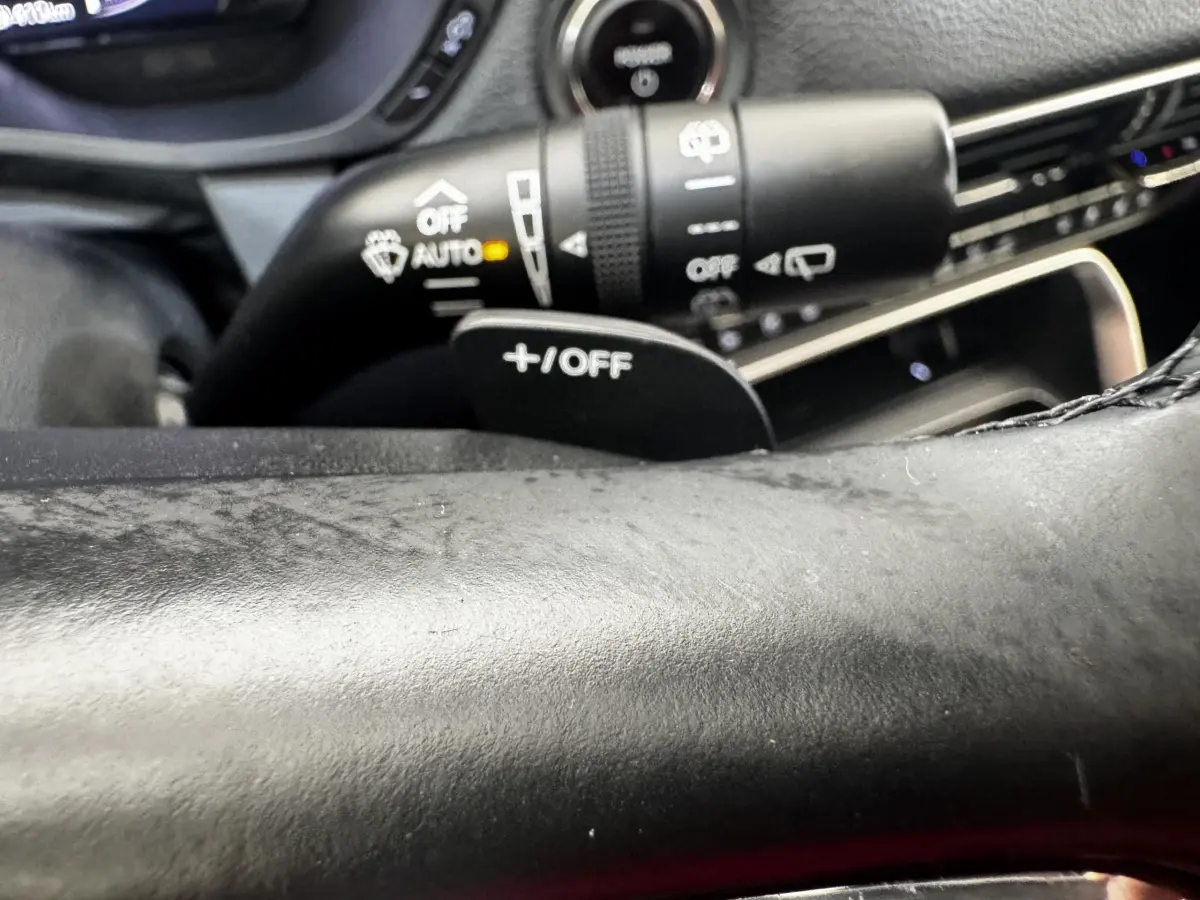 Gros plan sur le volant noir et la commande de régulateur de vitesse +/OFF du Mazda CX-60 2024 hybride rechargeable.