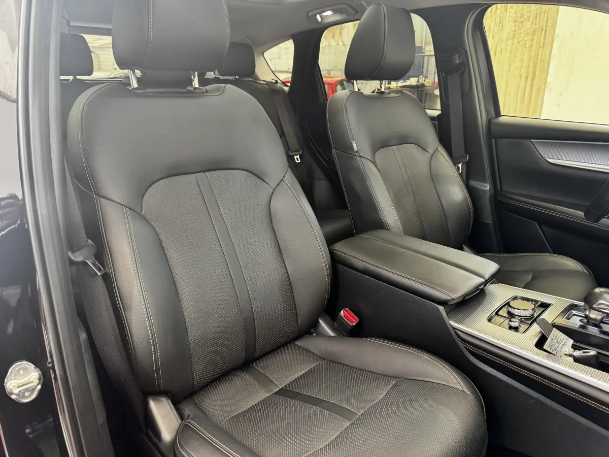 Vue intérieure côté conducteur du Mazda CX-60 noir 2024, sièges cuir noirs et console centrale avec molette de sélection.