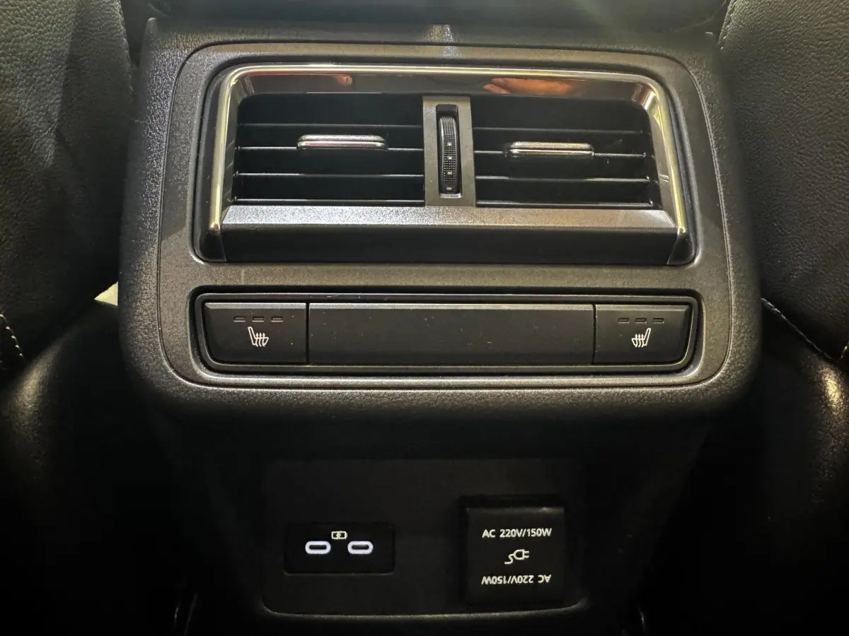 Vue rapprochée de la console arrière noire du Mazda CX-60 2024 avec aérateurs, commandes sièges chauffants et prises USB-C et AC.