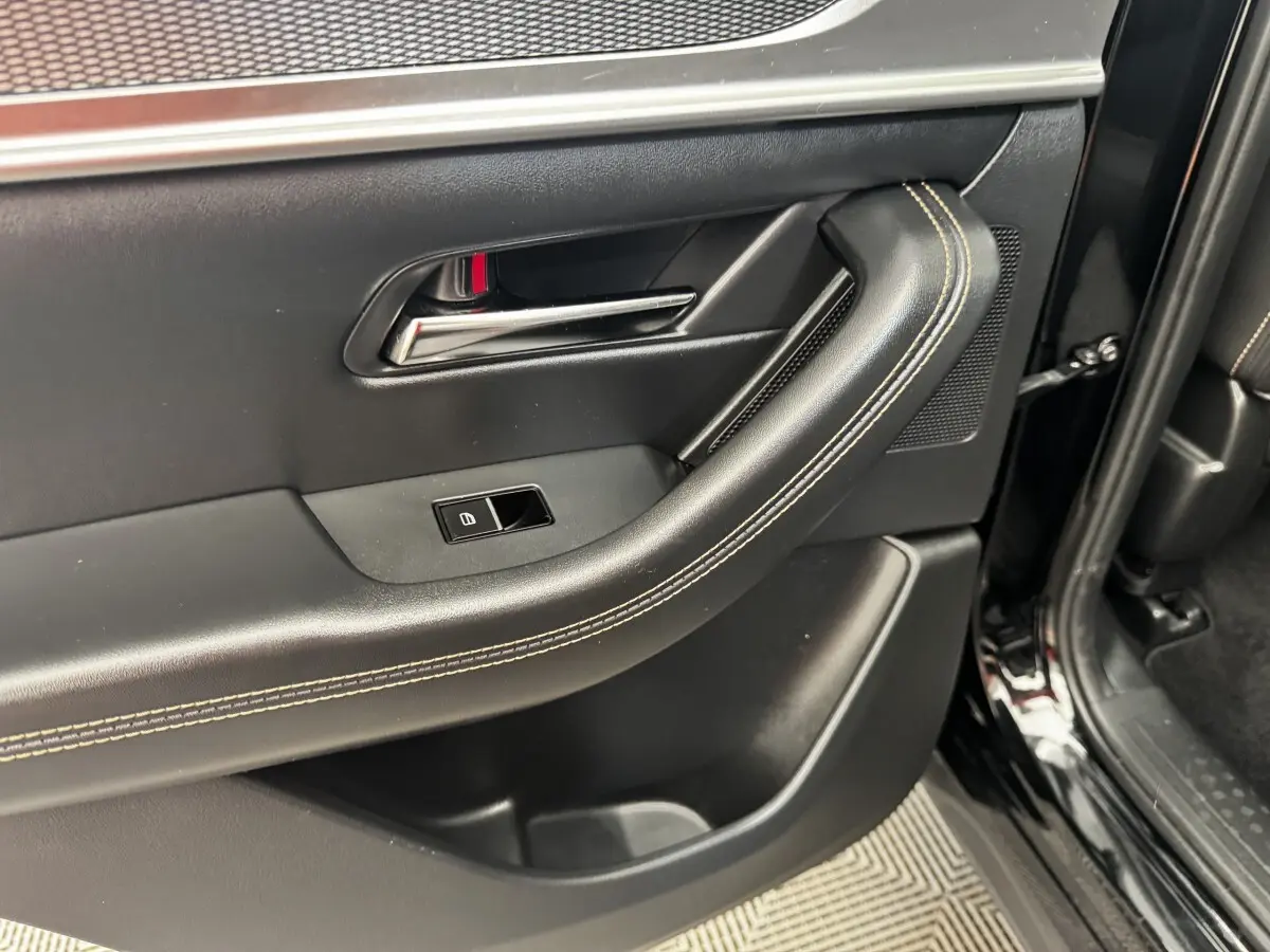 Vue rapprochée de la porte arrière droite noire du Mazda CX-60 2024, avec poignée intérieure et couture beige visible.