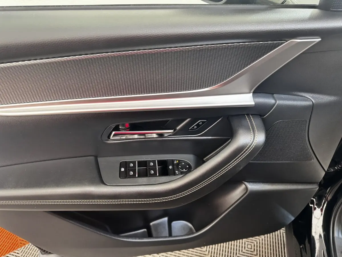 Vue rapprochée de la porte avant gauche noire du Mazda CX-60 2024, avec commandes de vitres et insert argenté.