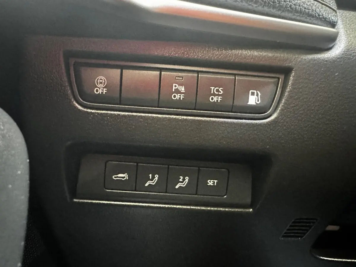 Gros plan sur les boutons de commande intérieurs du Mazda CX-60 noir, avec fonctions parking, traction et ouverture coffre.
