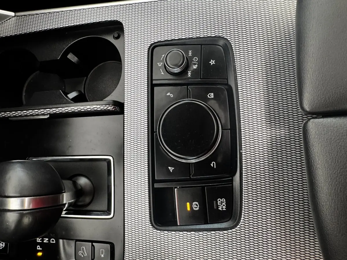 Vue rapprochée de la console centrale avec molette de sélection et levier de boîte automatique du Mazda CX-60 noir.