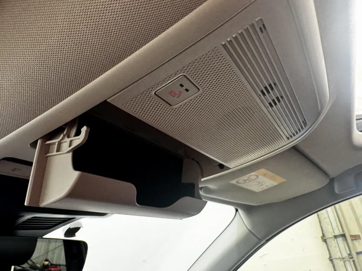 Détail intérieur du plafond de la Mazda CX-60 noir, montrant le rangement lunettes ouvert et le bouton SOS.