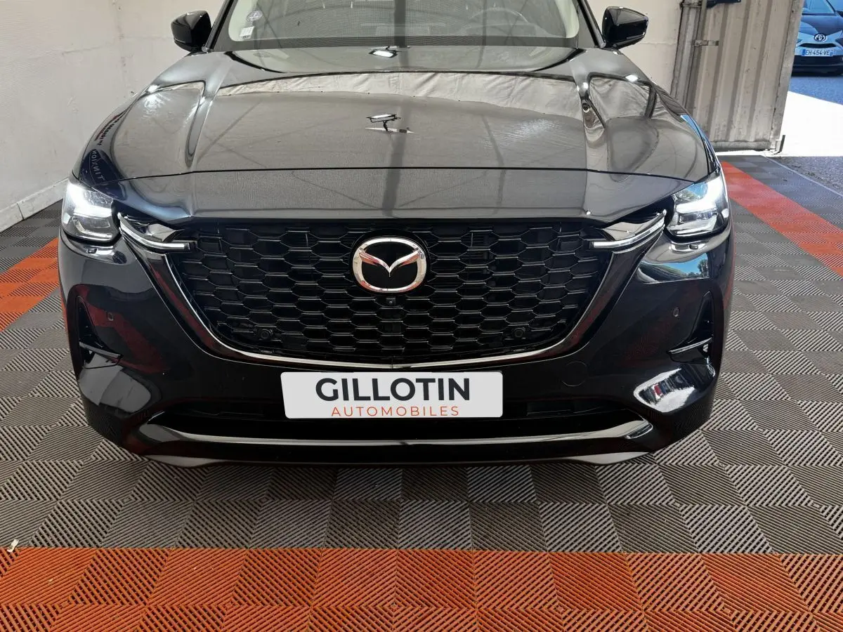 Vue frontale d'un Mazda CX-60 noir 2024 avec calandre hexagonale et phares LED allumés.