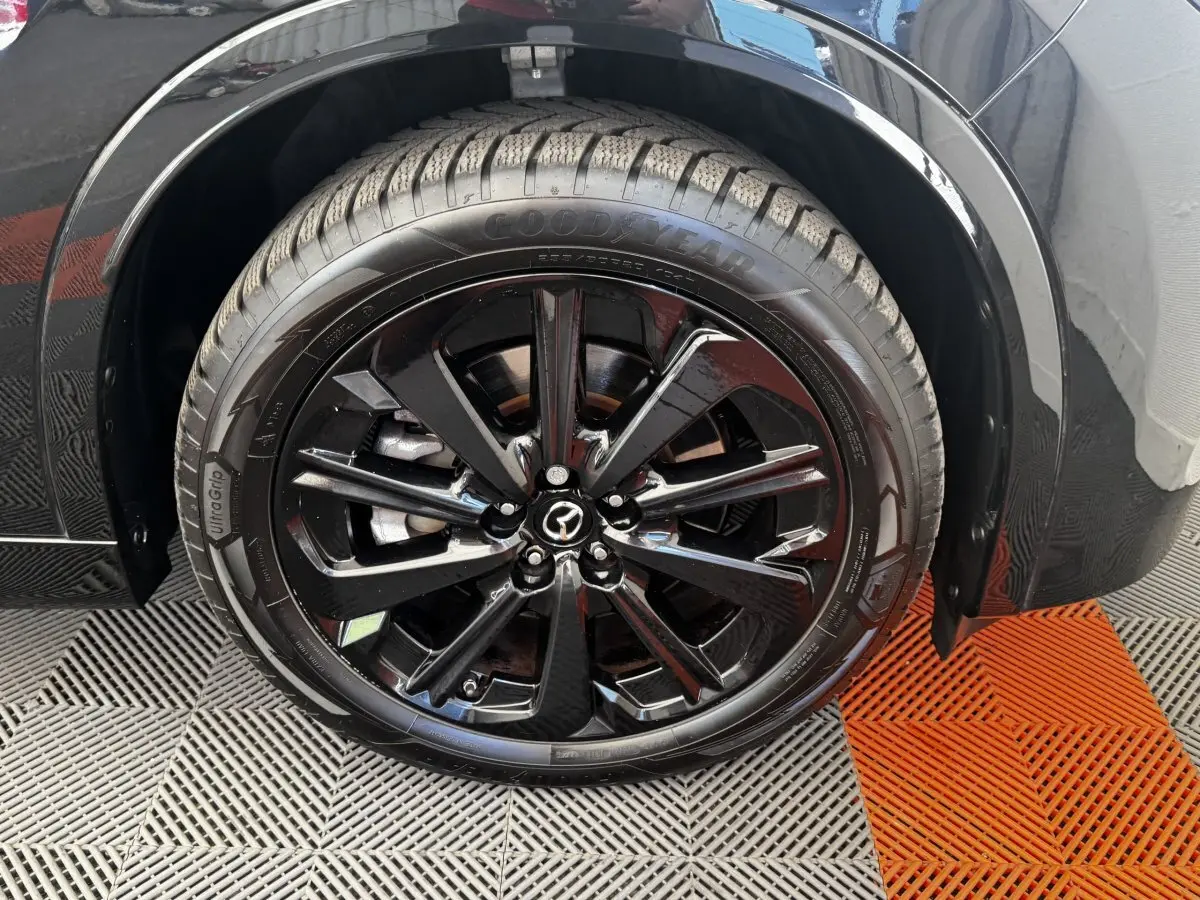 Gros plan sur la roue avant droite noire brillante du Mazda CX-60 2024 avec jante alliage et pneu Goodyear.