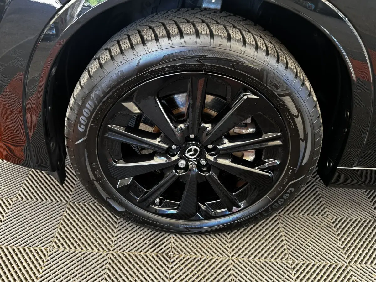 Gros plan sur la roue avant gauche noire avec jante alliage brillante du Mazda CX-60 2.5 e-Sky PHEV Homura 2024.