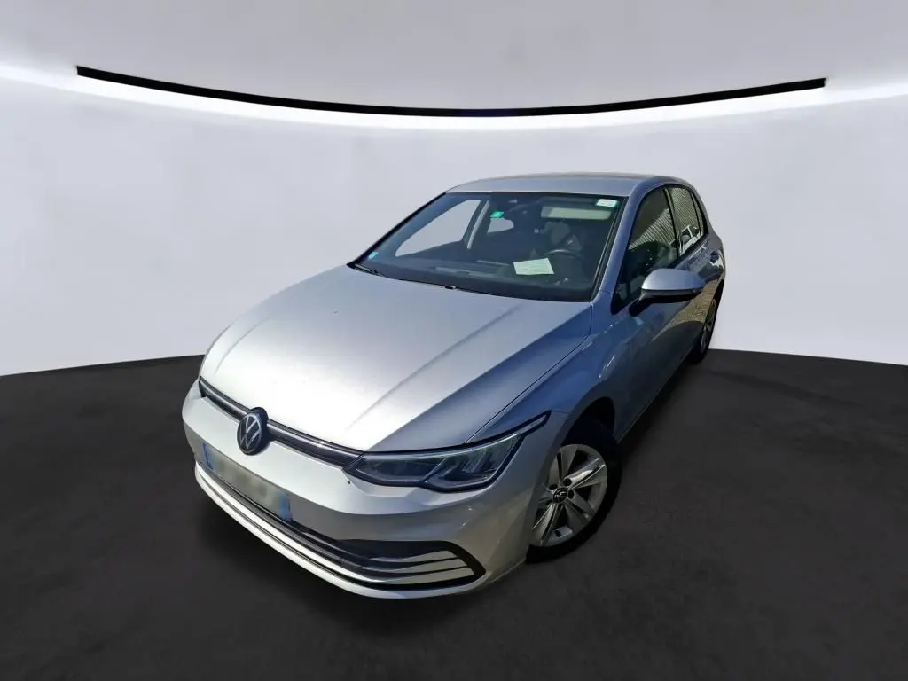 Volkswagen Golf gris clair vue 3/4 avant droit, mettant en valeur ses phares LED et la calandre épurée.