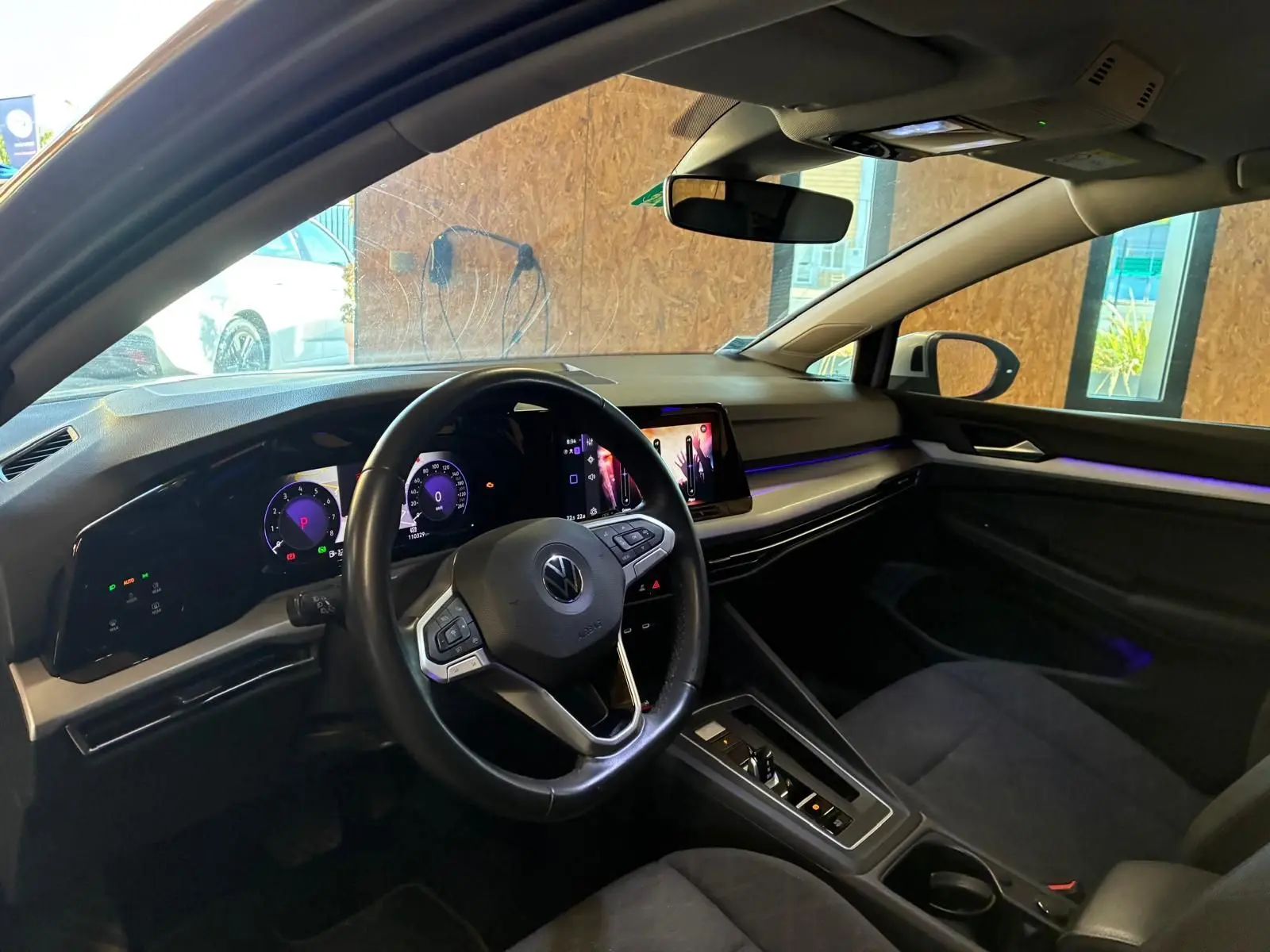 Vue intérieure côté conducteur de la Volkswagen Golf gris clair 2023, avec tableau de bord numérique et écran tactile central.