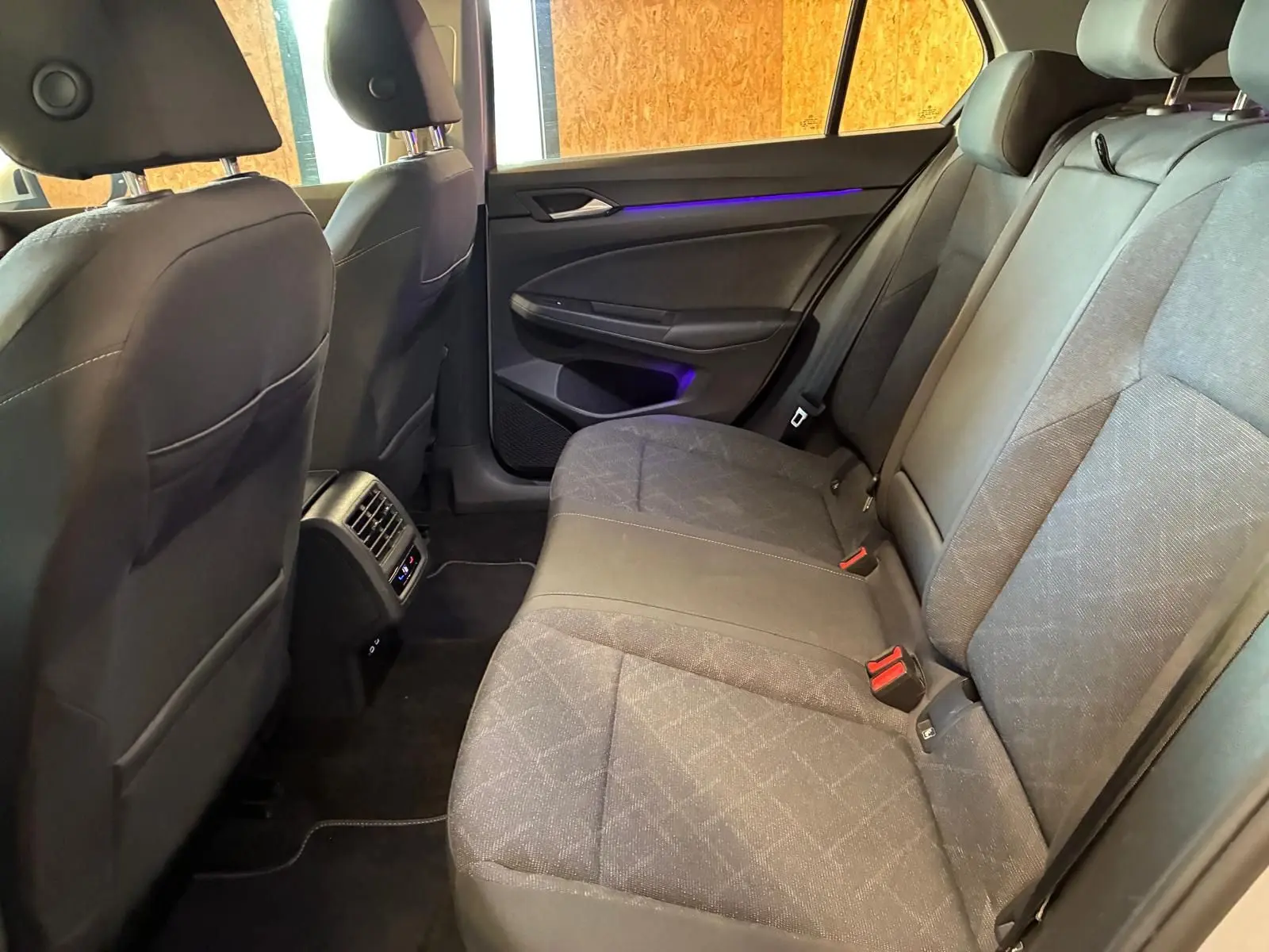 Vue intérieure arrière côté droit de la Volkswagen Golf 1.0 eTSI 110 DSG7 Life Plus 2023 avec sièges tissu gris et éclairage d'ambiance violet.