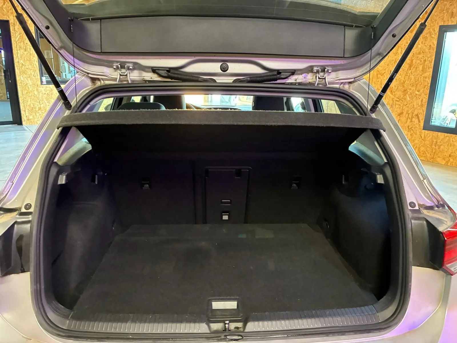 Coffre ouvert vu de l'arrière d'une Volkswagen Golf gris clair 2023, version 1.0 eTSI 110 DSG7 LIFE PLUS, intérieur noir.