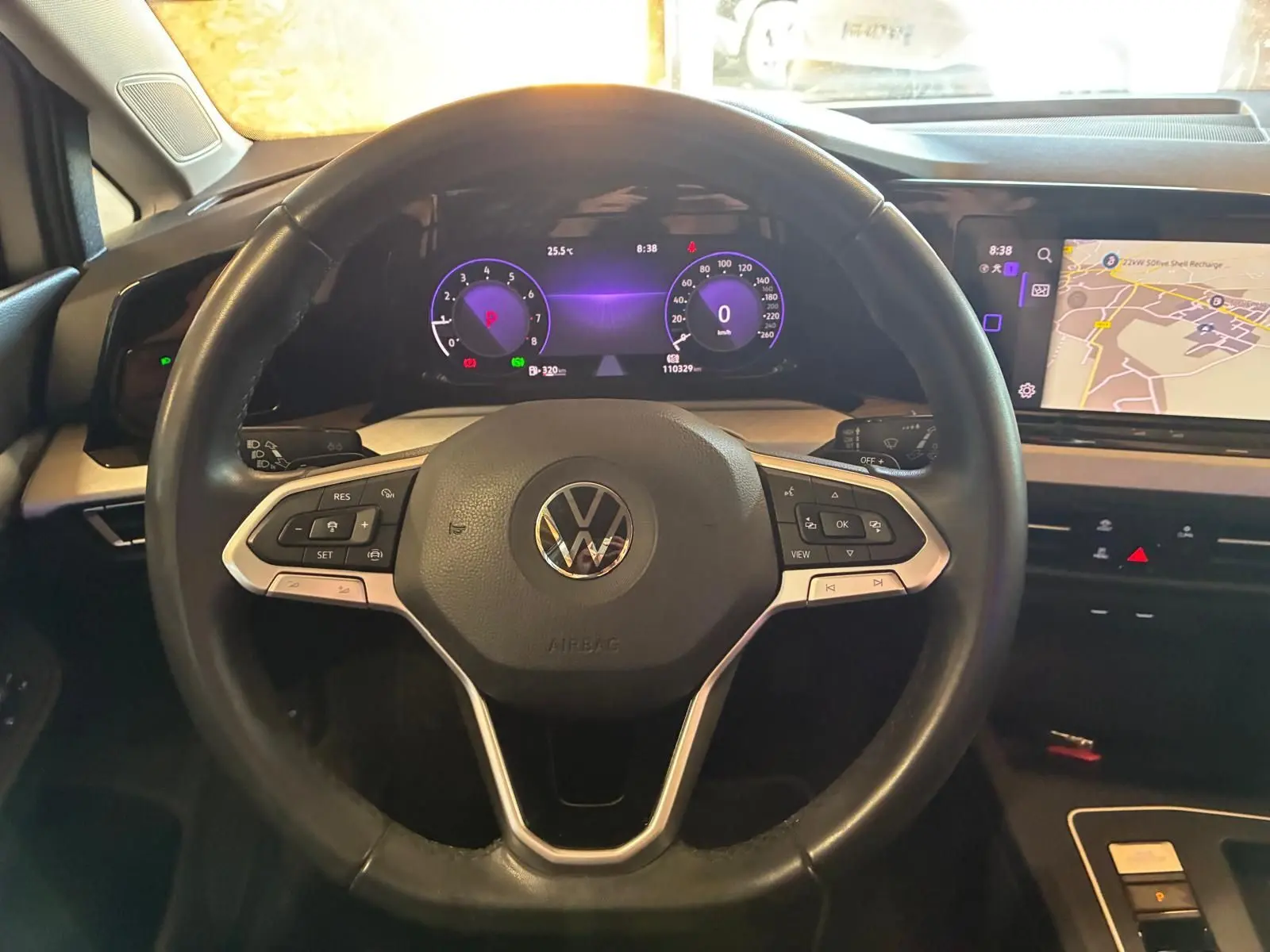Vue intérieure centrée sur le volant noir de la Volkswagen Golf 2023 avec tableau de bord numérique et écran de navigation.