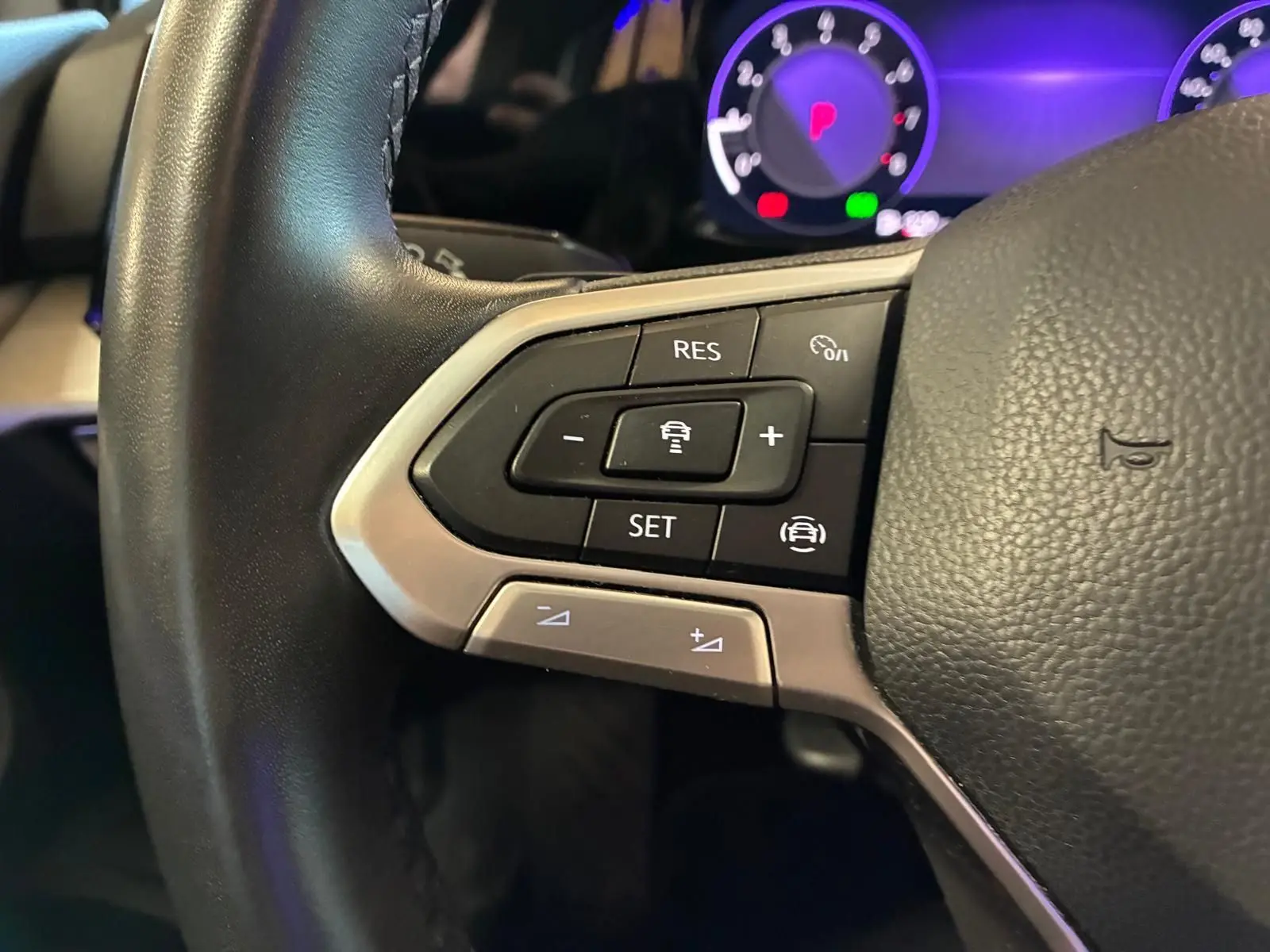 Gros plan sur les commandes au volant gauche de la Volkswagen Golf gris clair 2023, avec affichage numérique en arrière-plan.