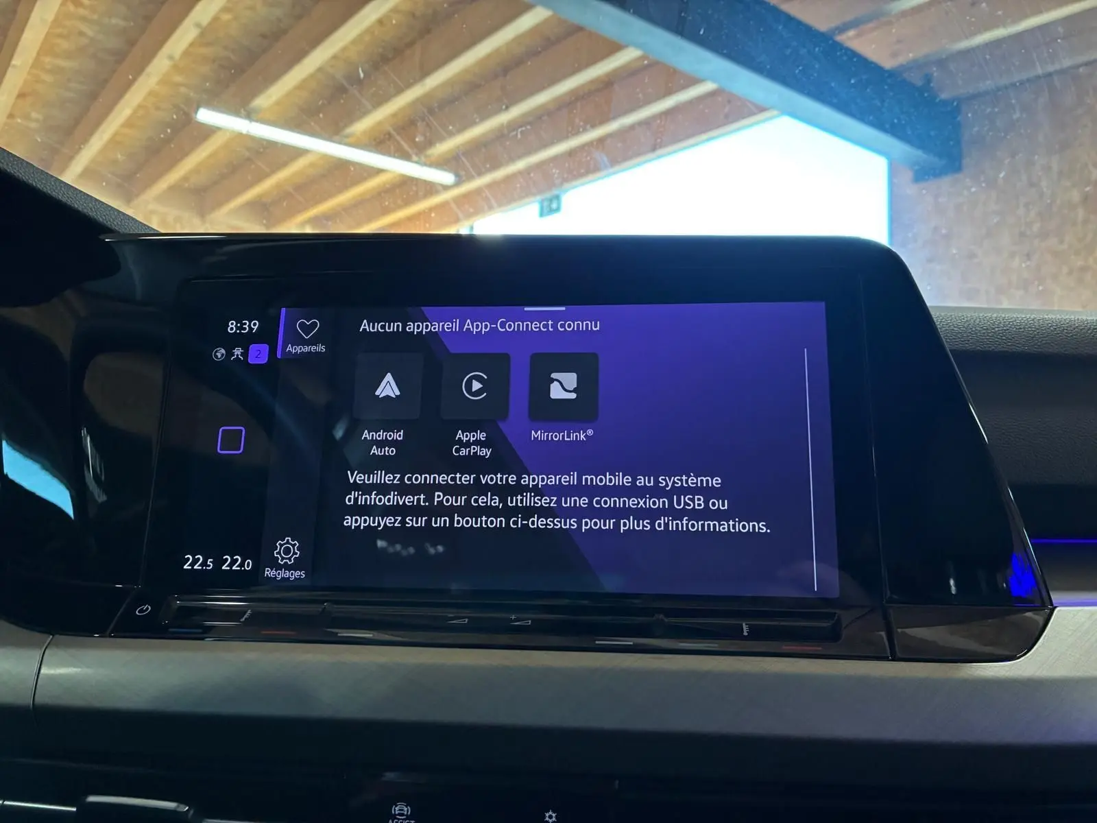 Vue rapprochée de l'écran tactile central du tableau de bord d'une Volkswagen Golf gris clair 2023, affichant les options App-Connect.