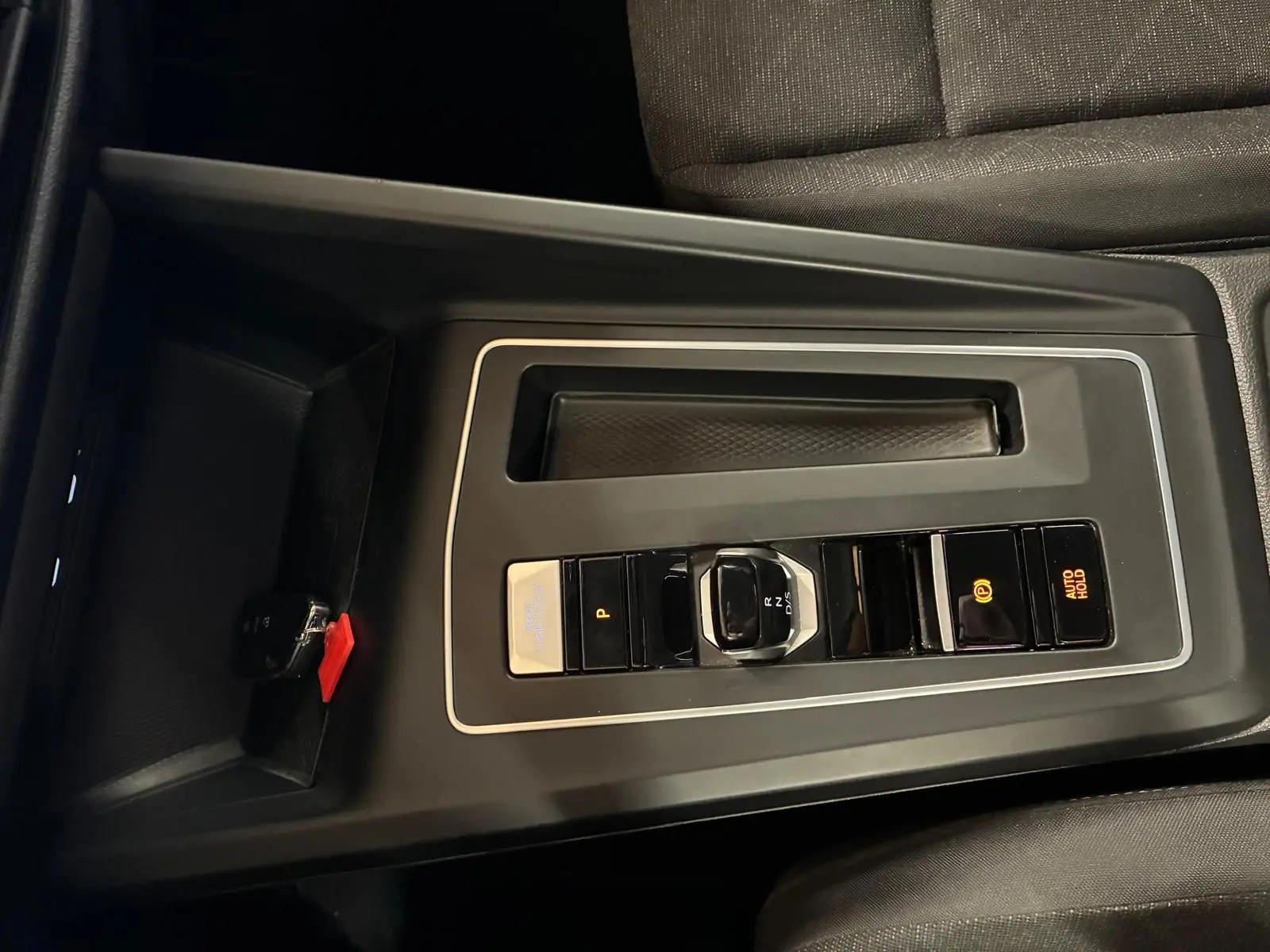 Vue rapprochée de la console centrale gris foncé de la Volkswagen Golf 2023 avec sélecteur de vitesse électronique et frein à main automatique.