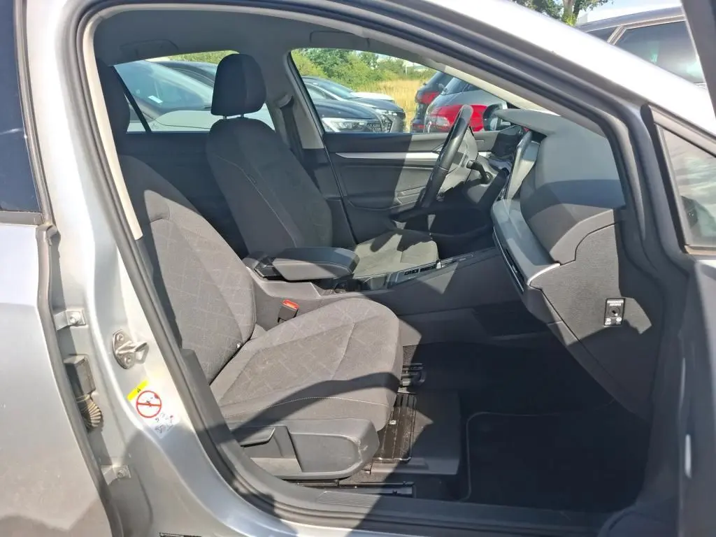 Vue intérieure côté conducteur de la Volkswagen Golf 1.0 eTSI 110 DSG7 Life Plus 2023 gris clair, sièges tissu gris et tableau de bord moderne.
