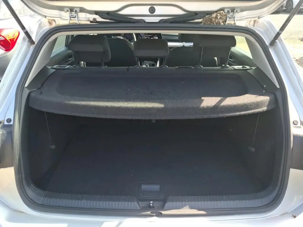 Coffre ouvert vu de l'arrière d'une Volkswagen Golf gris clair 2023, avec cache-bagages en place.