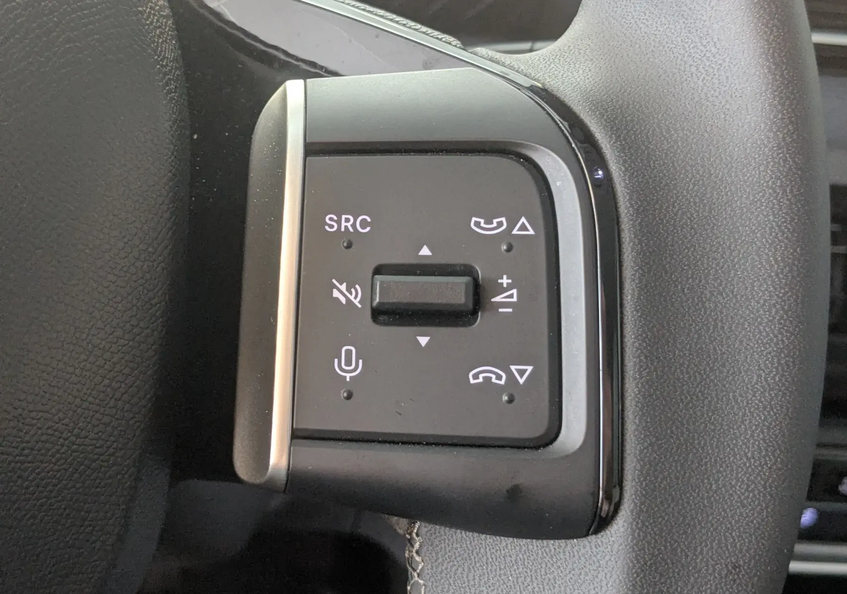 Gros plan sur les commandes noires du volant de la Citroën E-C3 113 MAX 2025, avec boutons de volume et appels.