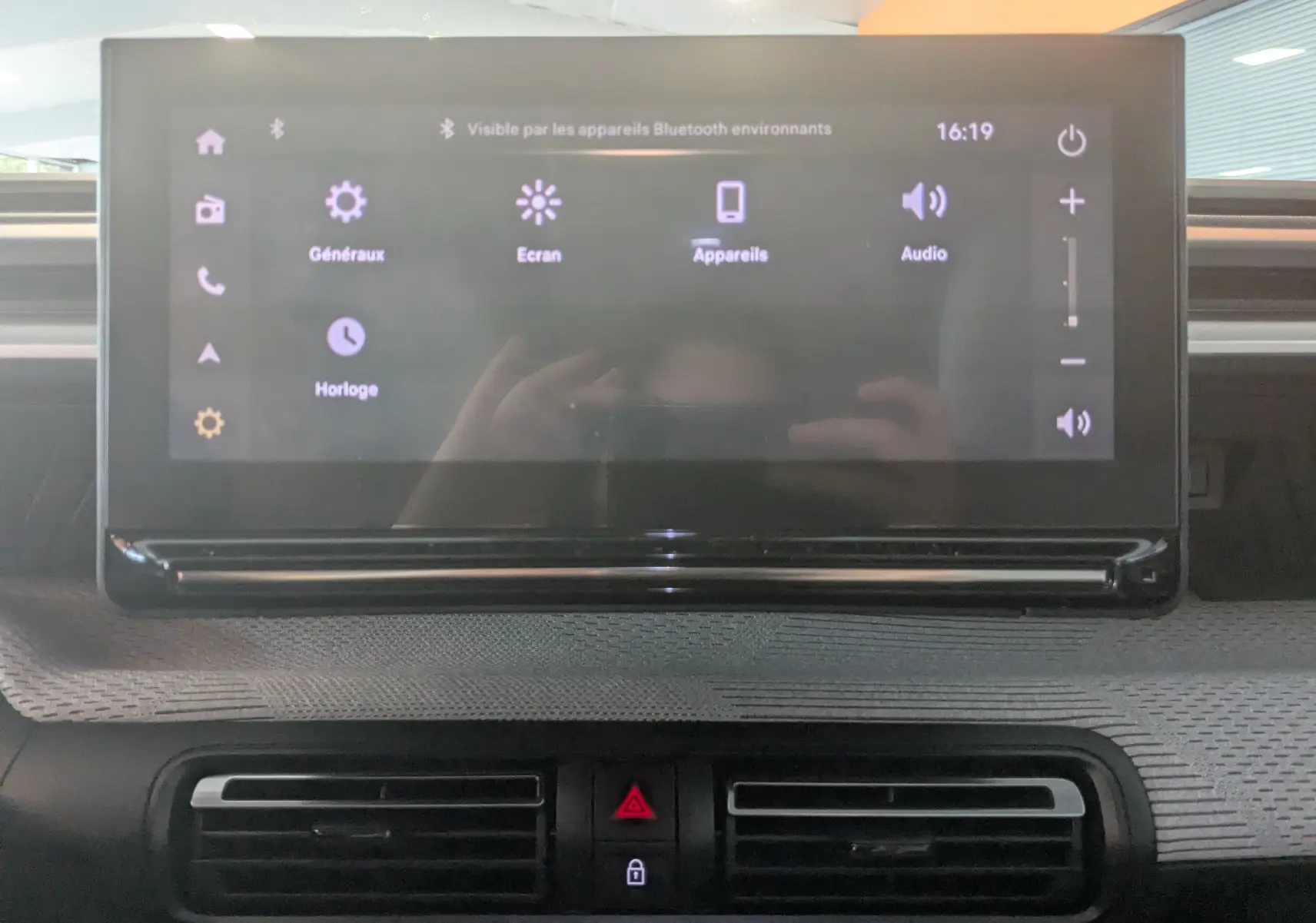 Écran tactile central allumé dans l'habitacle gris noir du Citroën E-C3 113 MAX 2025, avec commandes de climatisation visibles.