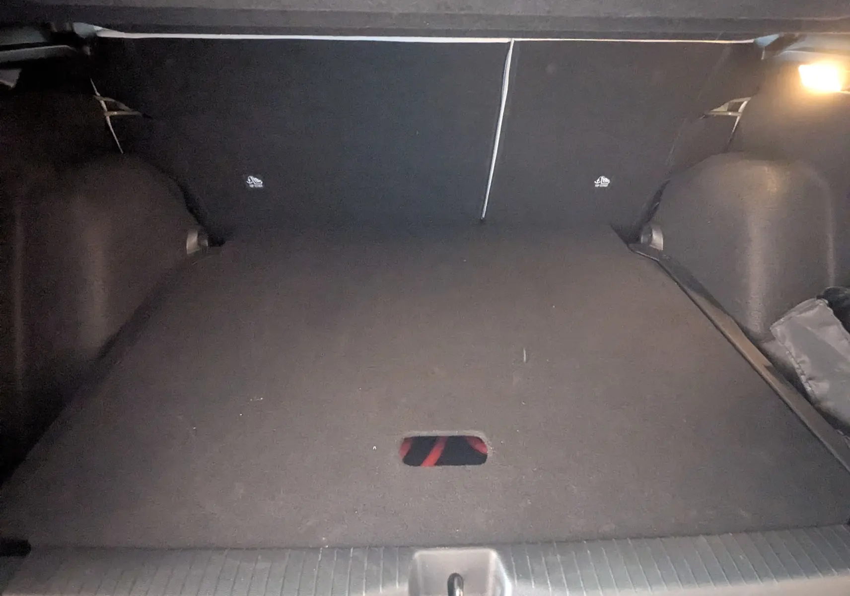 Coffre spacieux de la Citroën E-C3 113 MAX noir, vue intérieure arrière avec éclairage et tapis de sol noir.