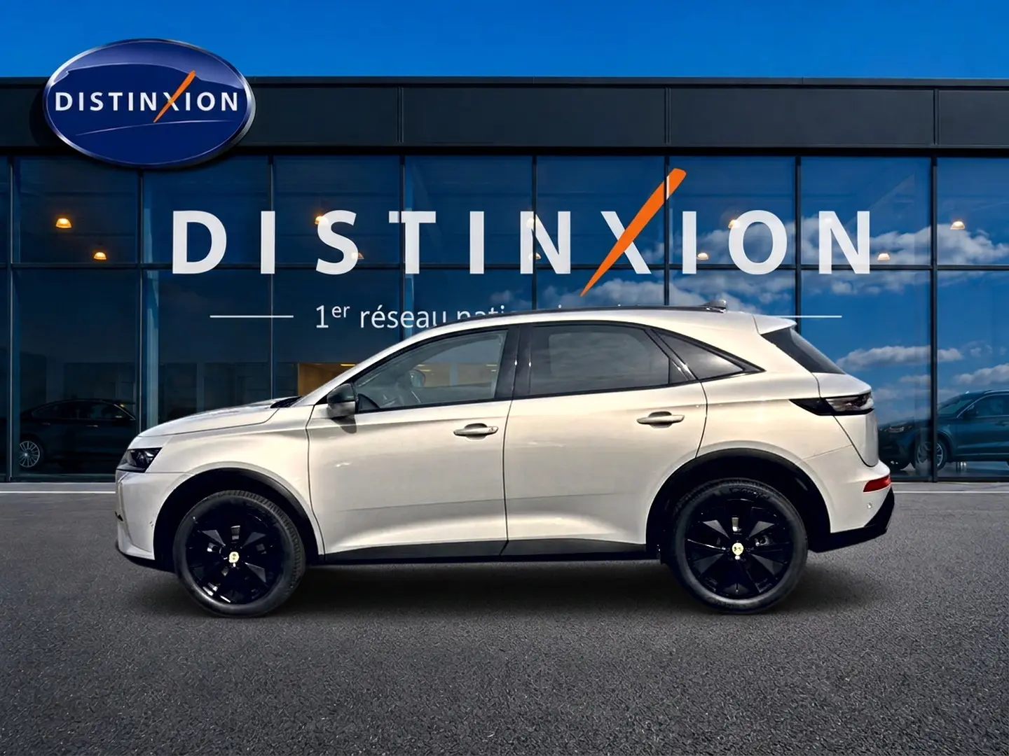 Vue de profil côté gauche du DS7 1.5 BlueHDi 130 Crystal Pearl avec jantes noires devant une vitrine Distinxion.