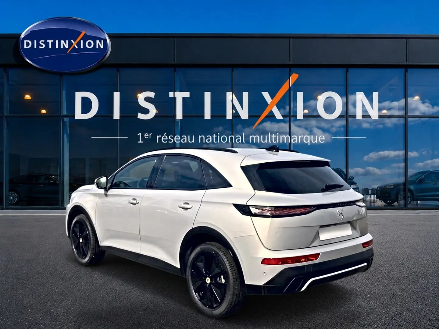 DS7 1.5 BlueHDi 130 Crystal Pearl vue 3/4 arrière droit avec jantes noires et vitres surteintées devant un showroom Distinxion.