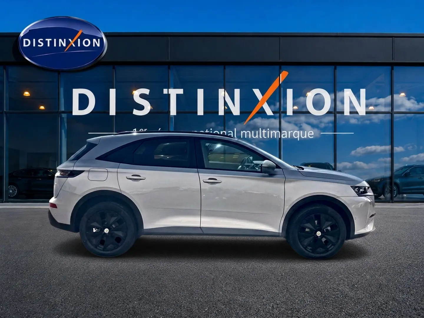 Vue latérale droite du DS7 1.5 BlueHDi 130 Crystal Pearl avec jantes noires devant une vitrine Distinxion.