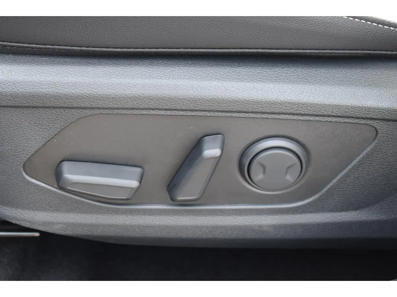 Gros plan sur les commandes électriques de réglage du siège avant du KIA SPORTAGE gris hybride 2026.