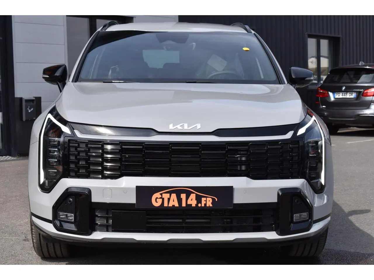 Vue de face du KIA Sportage gris 2026 avec calandre noire et feux LED verticaux distinctifs.