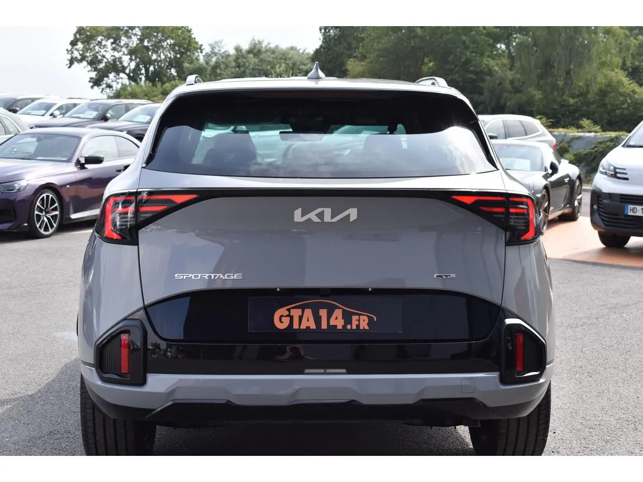 Vue arrière d'un Kia Sportage gris 2026 avec feux arrière LED et logo KIA visible sur le hayon.