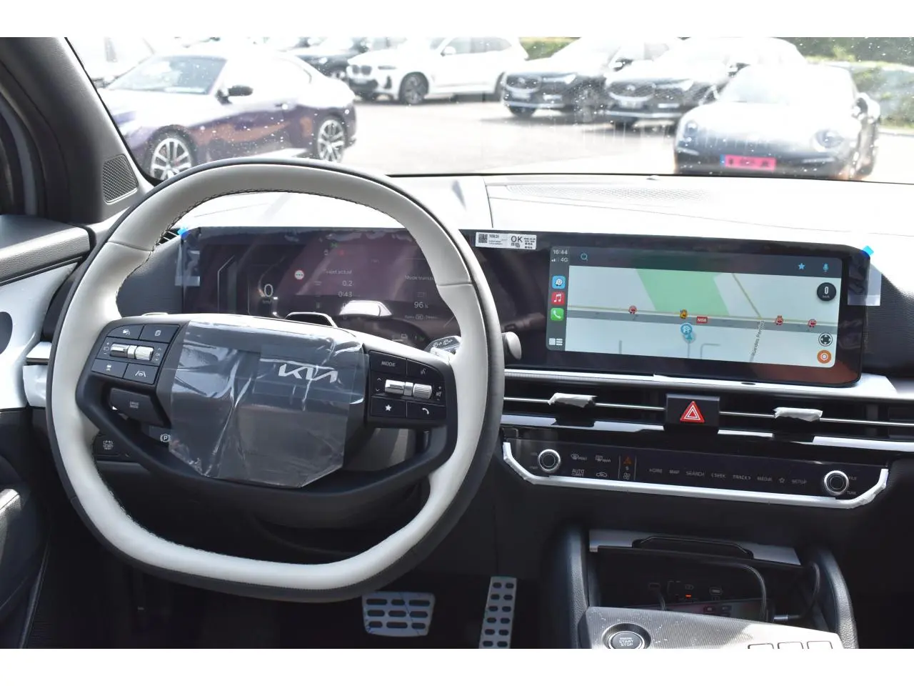 Intérieur du Kia Sportage hybride 2026 vu de face, tableau de bord avec écran tactile et volant bi-ton gris et noir.