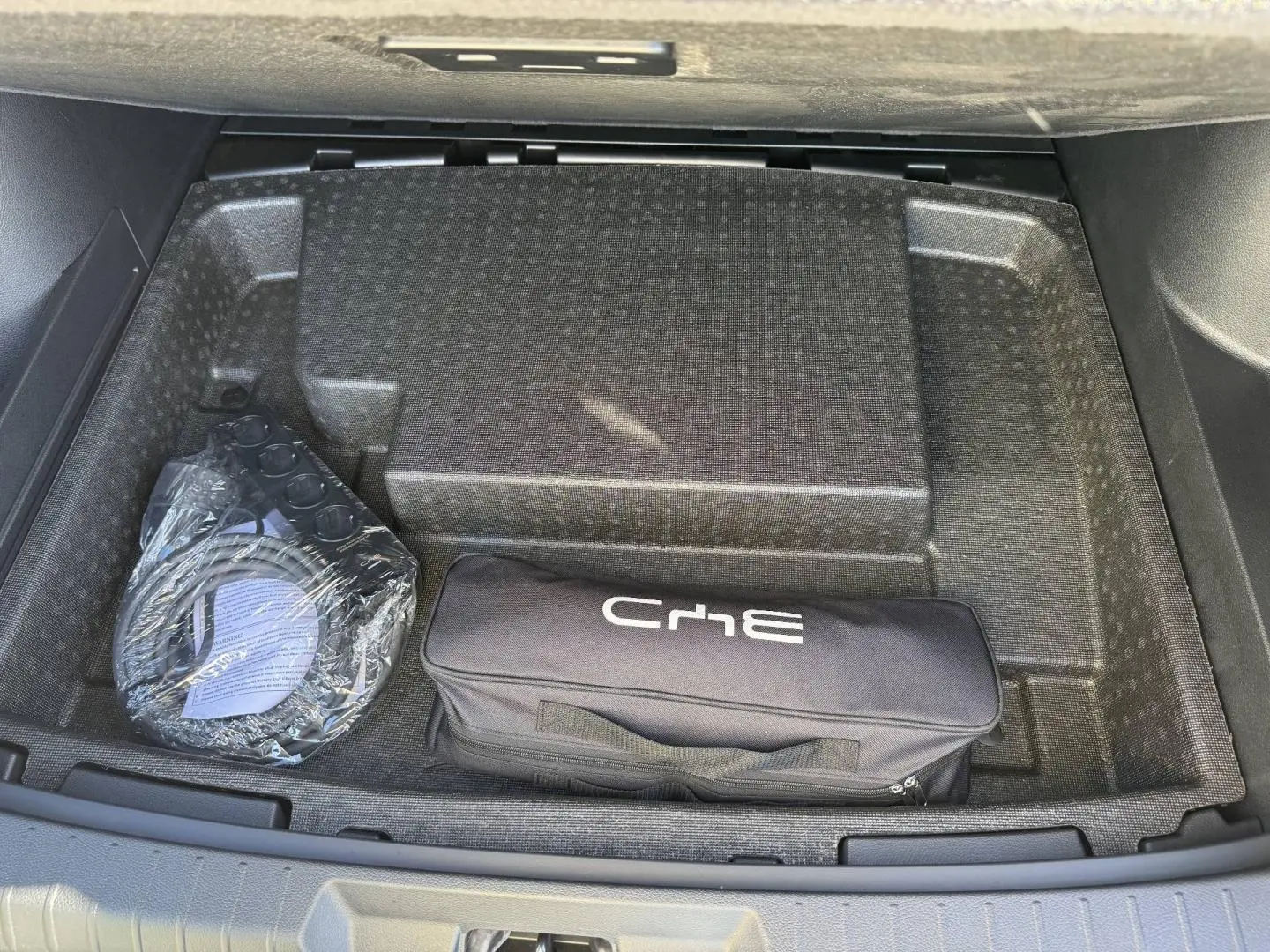 Coffre ouvert du BYD SEAL U 2026 en Obsidian Black, montrant un rangement avec sac de chargement et câble emballé.