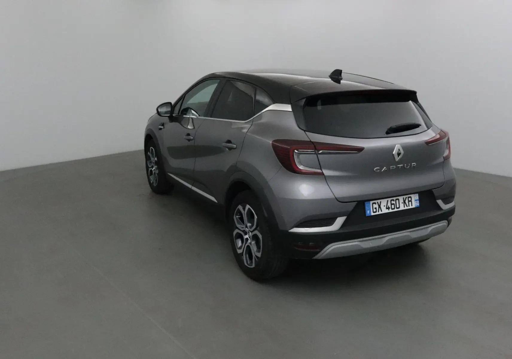Renault Captur 2024 gris Cassiopée et noir, vue 3/4 arrière droit, avec feux arrière LED et jantes alliage 18 pouces.