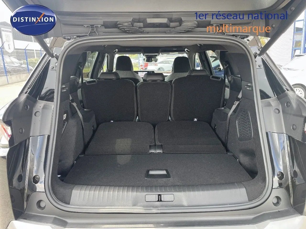 Coffre ouvert du Peugeot 5008 noir perle métal, montrant les sièges arrière rabattus et l'espace de chargement spacieux.