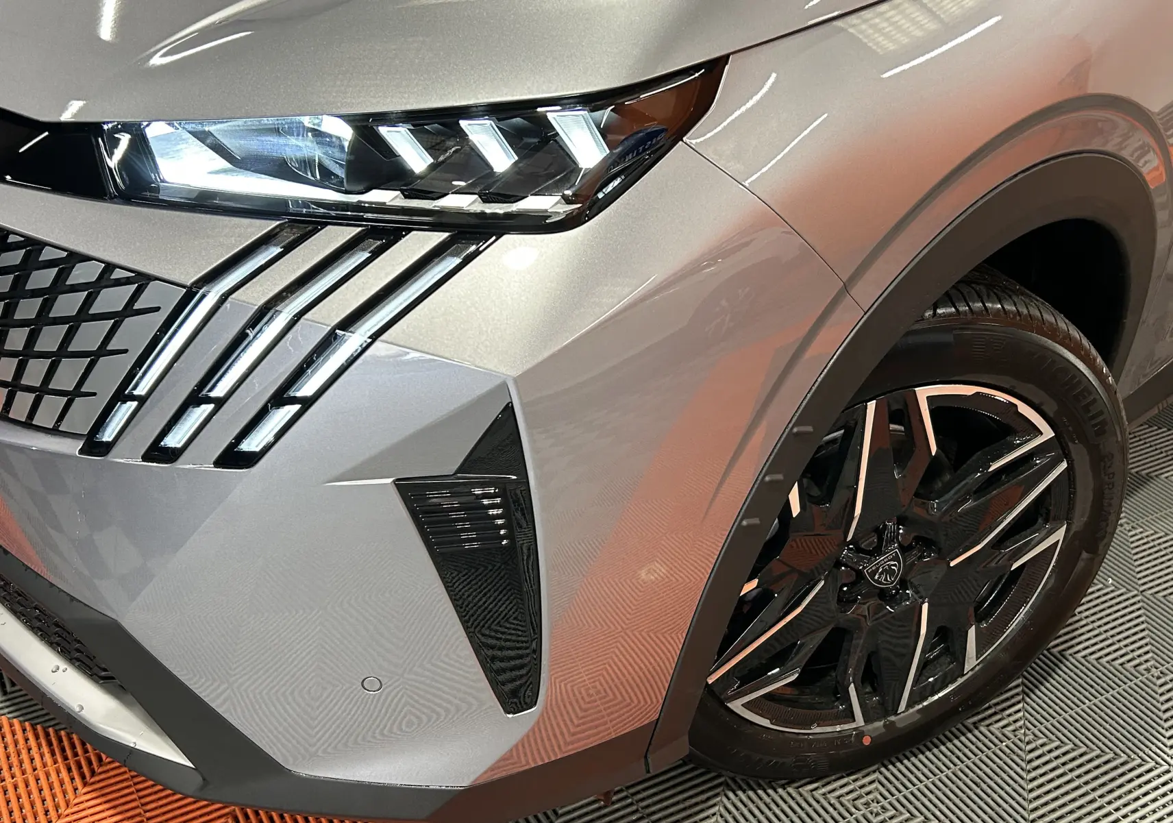 Gros plan sur l’avant droit du Peugeot 3008 gris Artense, mettant en valeur les phares LED et la jante noire brillante.
