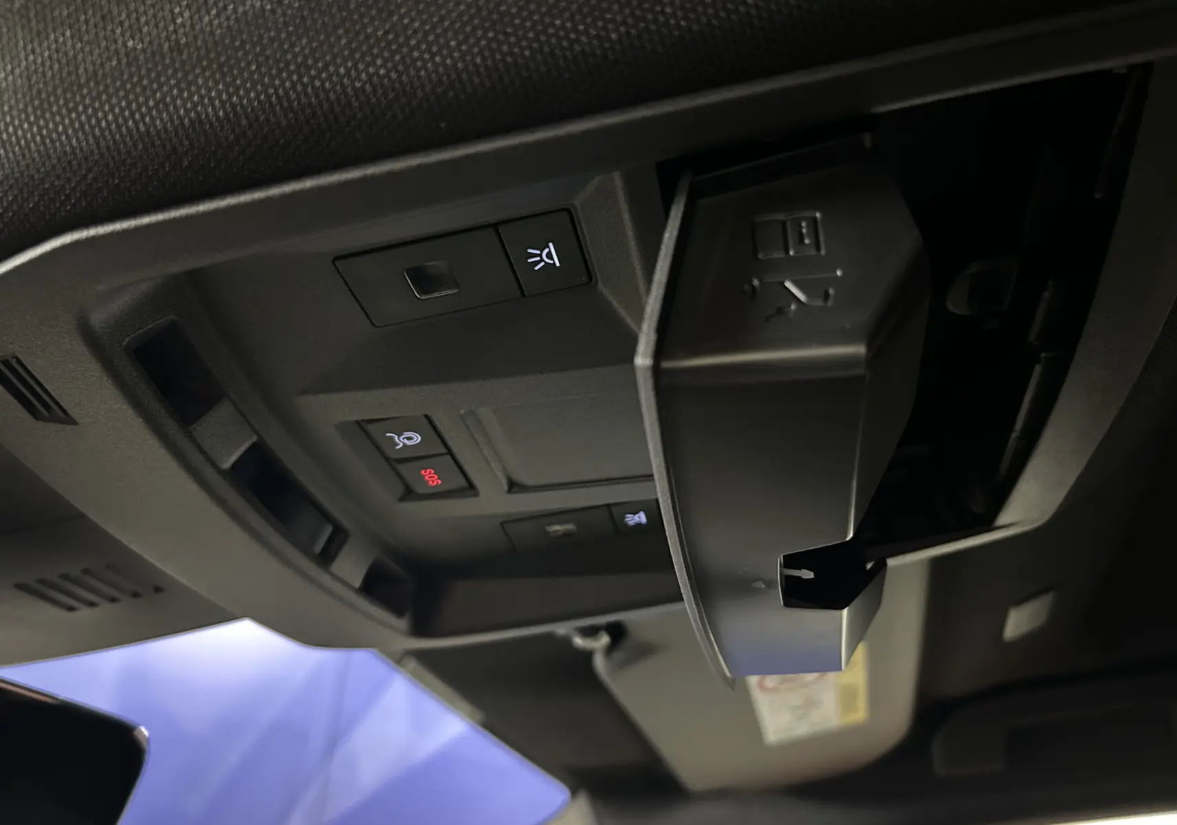 Vue intérieure en plongée du plafonnier noir avec commandes d’éclairage et bouton SOS du Peugeot 3008 gris Artense.