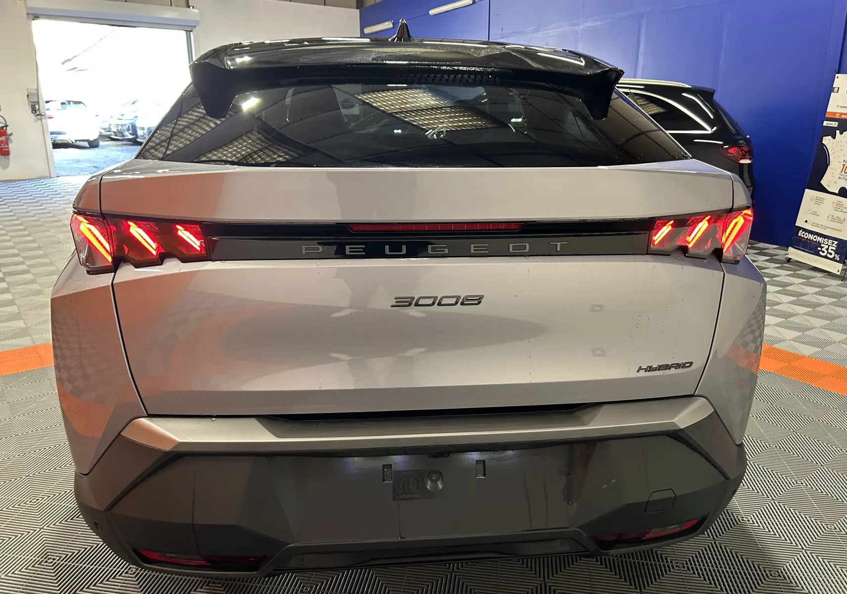 Vue arrière d’un Peugeot 3008 gris Artense avec feux LED allumés dans un garage intérieur.