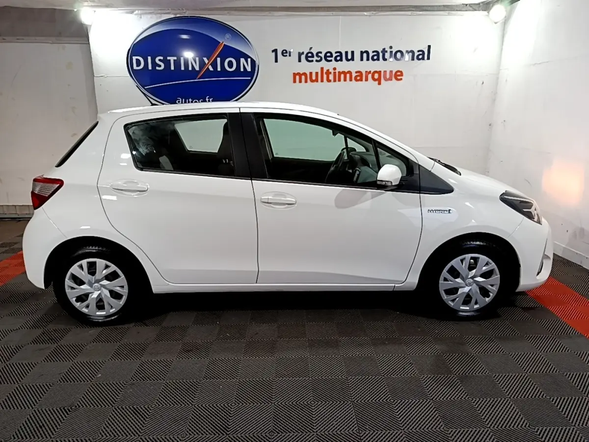 Profil droit d'une Toyota Yaris blanche 2020 hybride, avec jantes alliage et badge Hybrid visible sur l'aile avant.