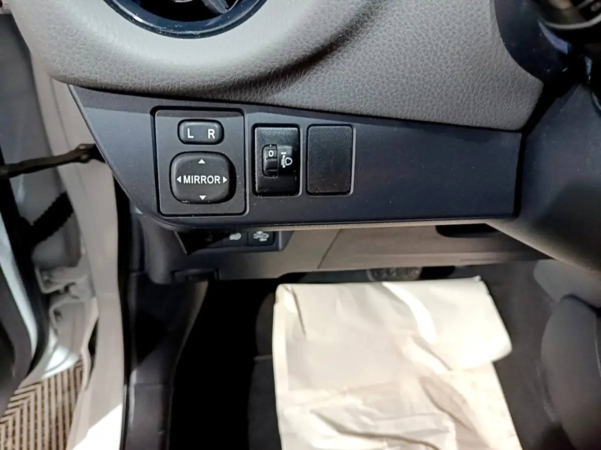 Vue rapprochée du tableau de bord côté gauche de la Toyota Yaris blanche, avec commandes réglage des rétroviseurs.