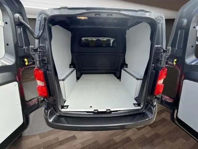 Vue arrière ouverte du Citroën Jumpy gris titane, montrant l'aménagement bois clair du coffre avec coffrages latéraux.