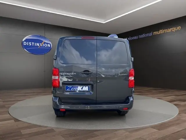 Vue arrière d'un Citroën Jumpy gris titane 2026 avec portes battantes et feux arrière LED dans un showroom.