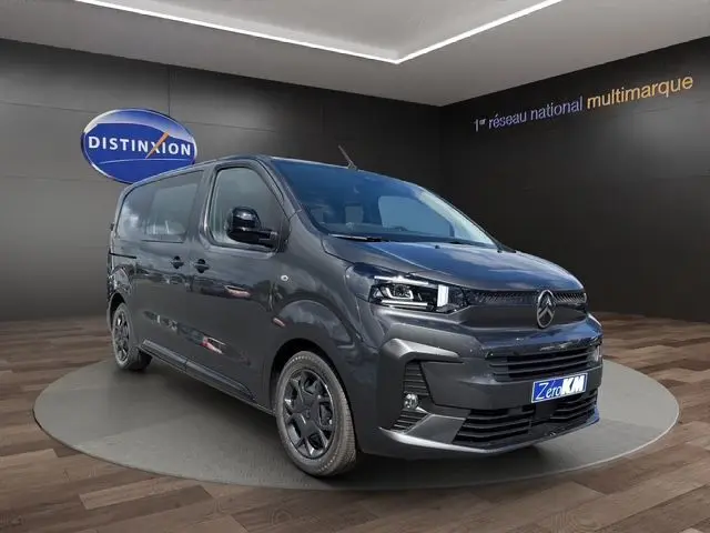 Vue 3/4 avant droite du Citroën Jumpy gris titane avec pack look et projecteurs full LED dans un showroom.