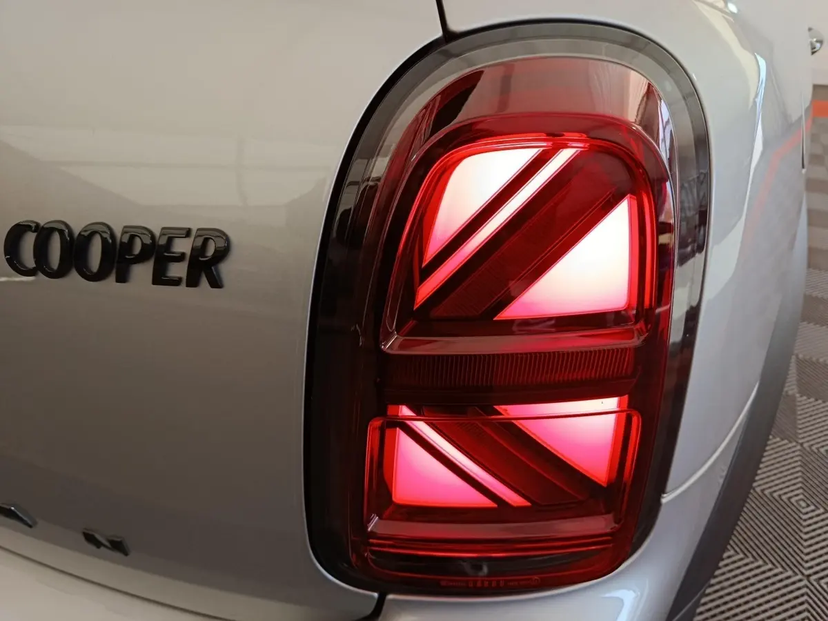 Gros plan sur le feu arrière droit rouge et le logo Cooper sur la carrosserie gris foncé du MINI Countryman 2023.