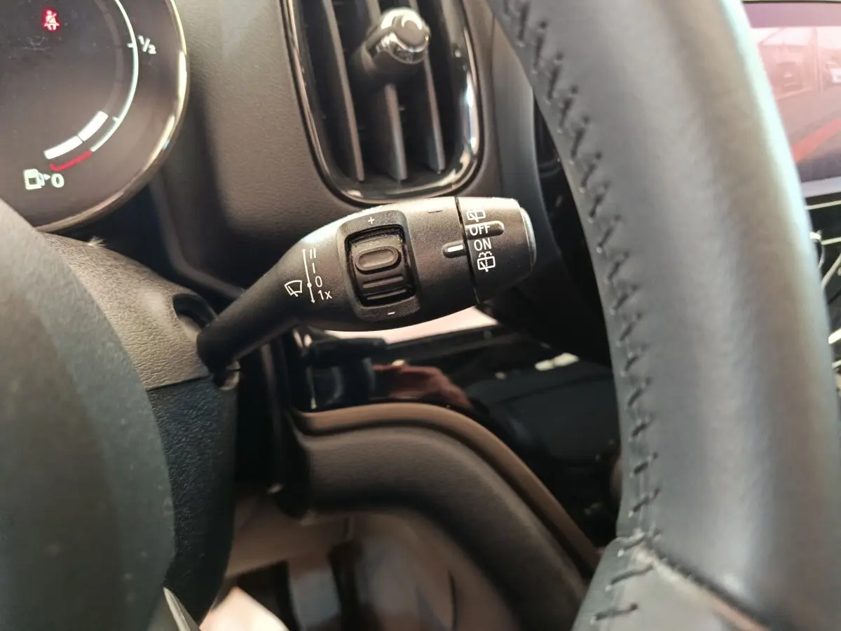 Gros plan sur la commande d’essuie-glace à gauche du volant cuir dans l’habitacle noir du MINI Countryman gris foncé 2023.