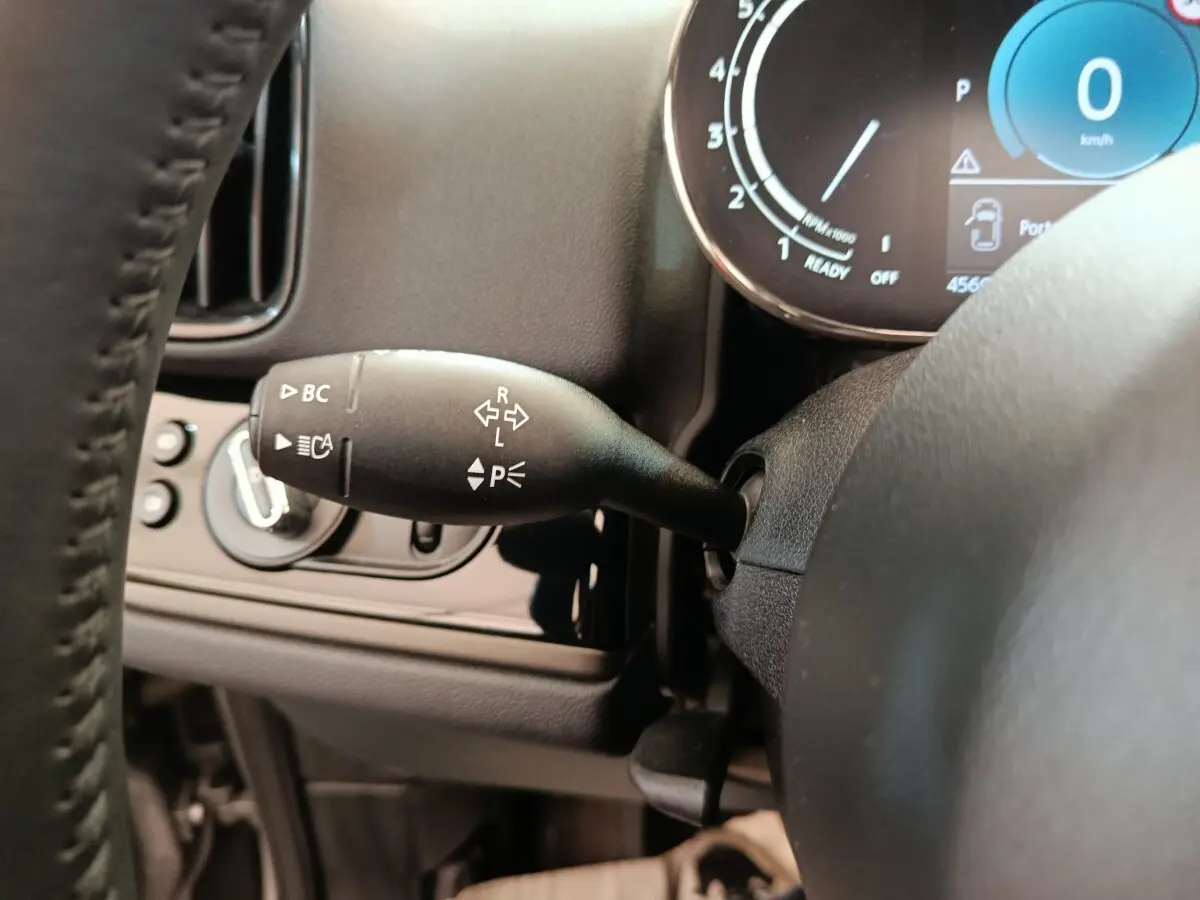 Gros plan sur la commande de clignotants à gauche du volant du MINI Countryman gris foncé, avec tableau de bord digital visible.